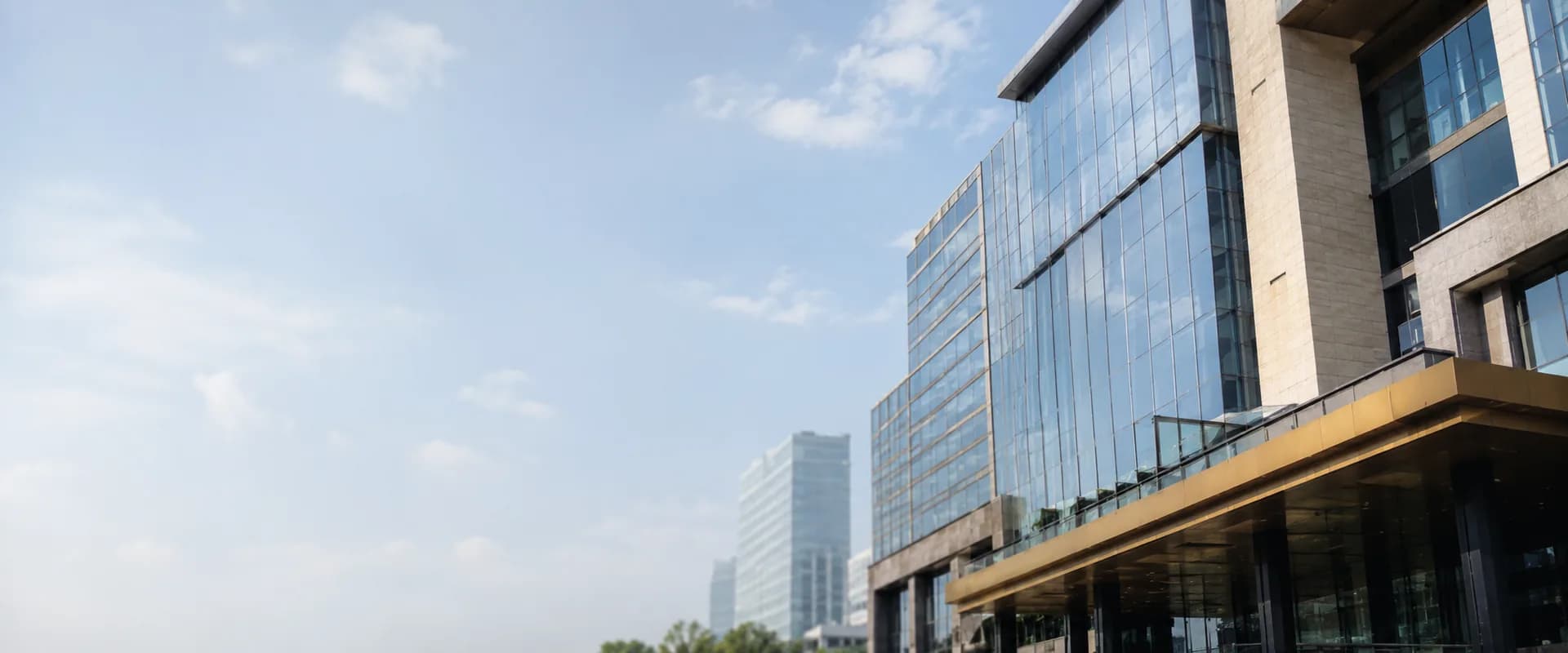Modern glass corporate office tower in an Indian financial district, photographed from below against a clear sky